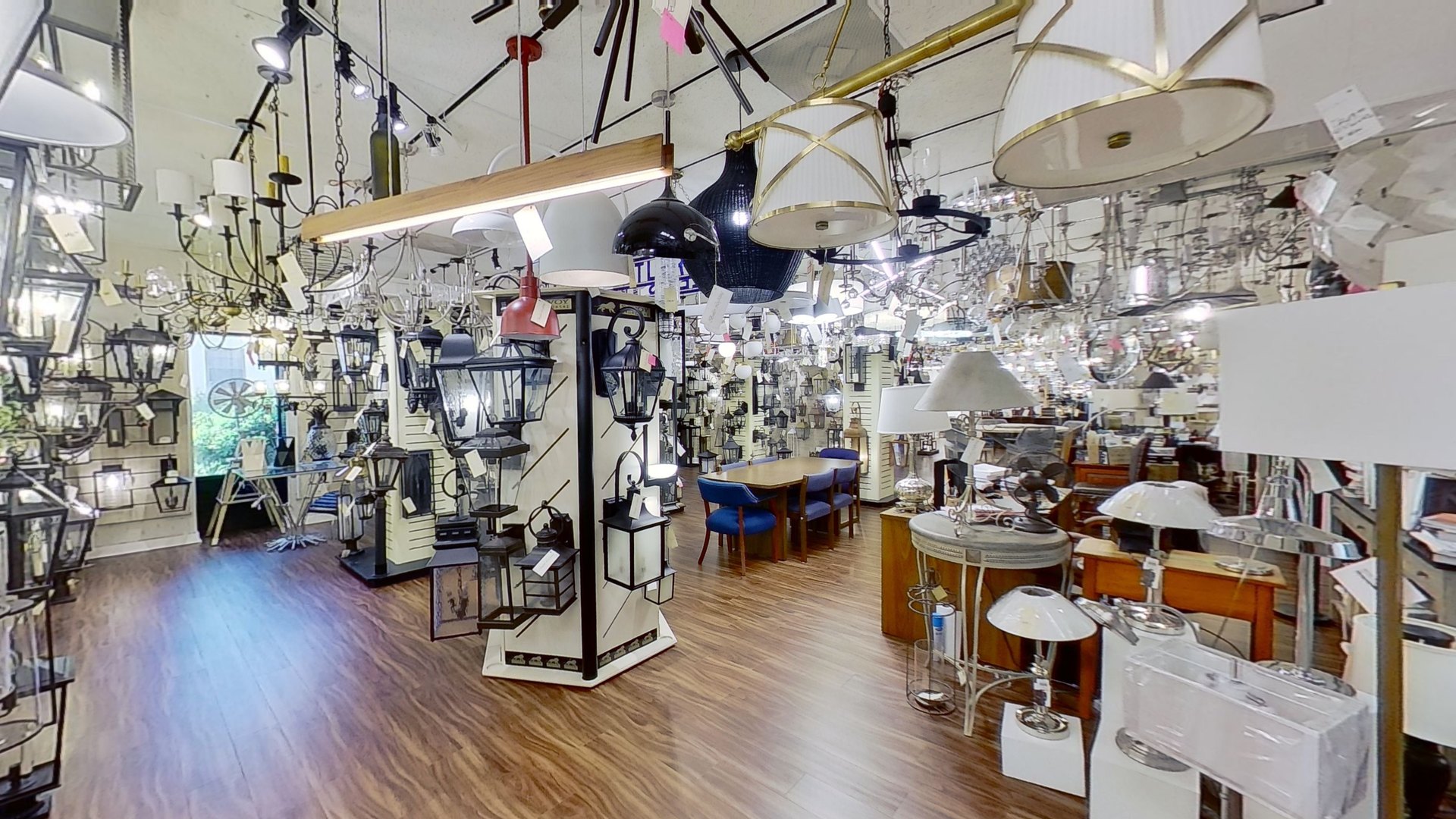 Lanterns, pendants, and table lamps packed along a High Point showroom aisle